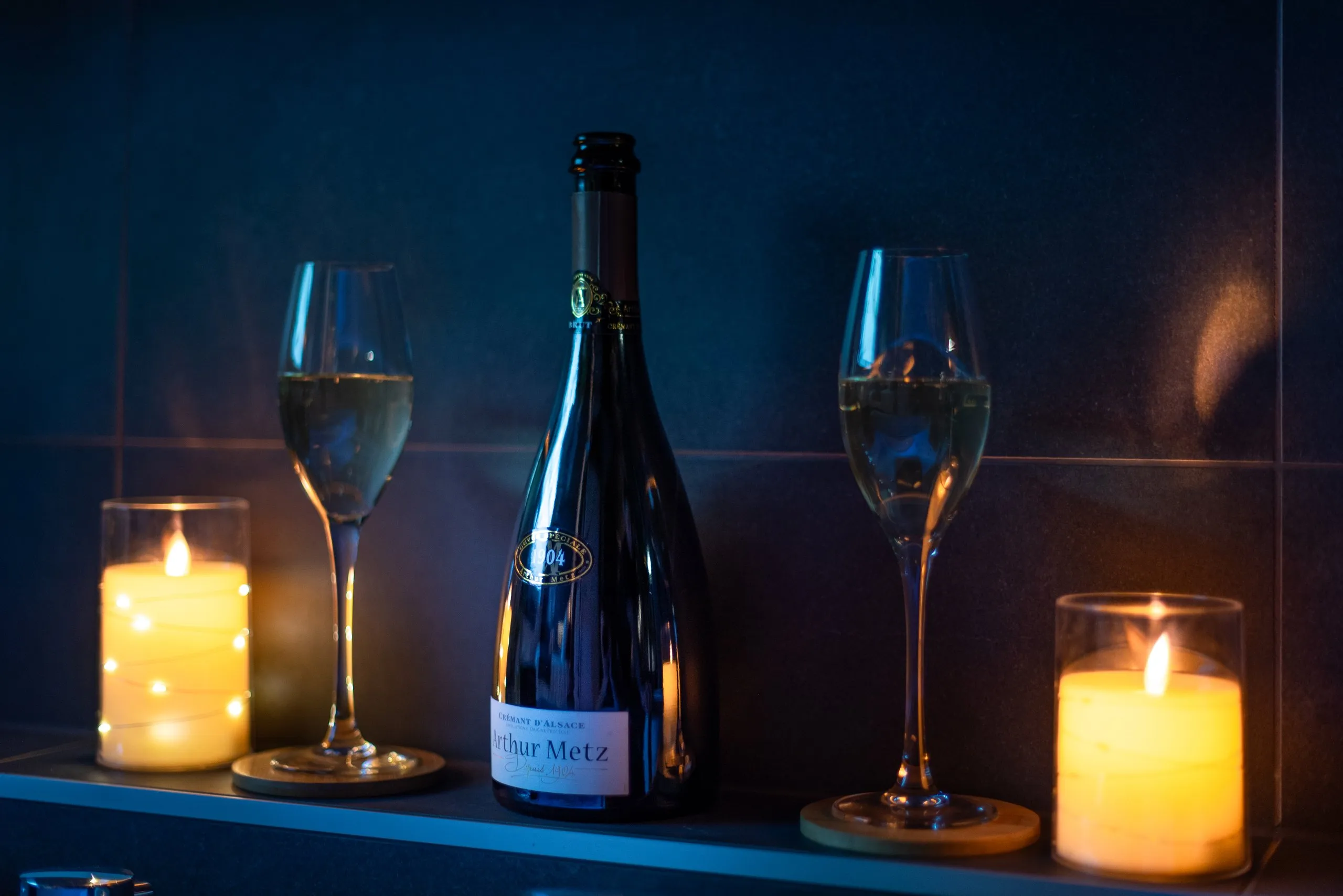 Une bouteille de crémant, deux coupes et des bougies au bord de la balnéo